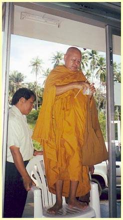 A monk paints magic signs on the door for good luck